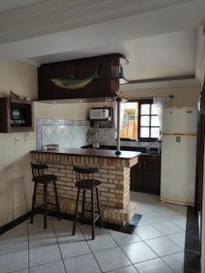 uma cozinha com um bar de tijolos com bancos e um frigorífico em Cabelera's House em Bombinhas