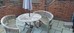 een tafel en 2 stoelen met een parasol op een patio bij Blashford Manor Farmhouse - The Shetland Cottage in Ringwood