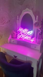 a room with a table with a pink lighted mirror at The Rose Garden Room - self contained studio in Ballycastle