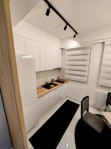 La cuisine est équipée de placards blancs, d'un évier et d'une chaise. dans l'établissement A'dors Apartments - Bed, Breakfast & Spa, à Skopje