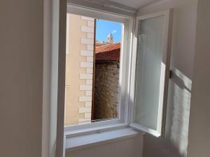 a window with a view of a brick building at Four Towers Apartments in Rab
