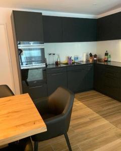 a kitchen with black cabinets and a wooden table at Schöne stilvolle 45 Garten Ferienwohnung im Melchtal Kerns in Melchtal