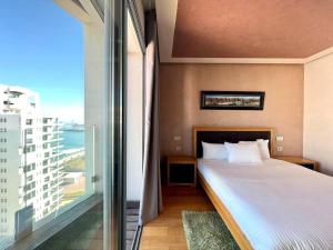 a bedroom with a bed and a large window at The Panorama of Marina - AppartAli in Casablanca