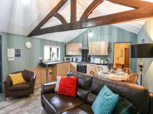 a living room with a leather couch and a kitchen at Field View at Coomb Bank Farm in Axminster