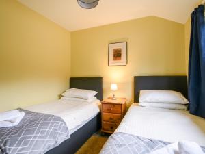 two twin beds in a room with a night stand at Field View at Coomb Bank Farm in Axminster
