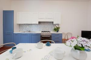 eine Küche mit blauen Schränken und einem Tisch mit Blumen in der Unterkunft Villetta La Conchiglia Man in San Teodoro