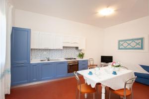 uma cozinha com armários azuis e uma mesa com cadeiras em Villetta La Conchiglia Man em San Teodoro