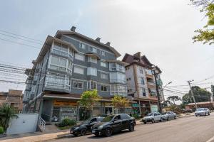 un grand bâtiment avec des voitures garées devant dans une rue dans l'établissement Serra Nevada Apartamento - Vista Catedral de Pedra, à Canela