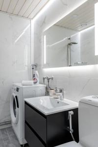 a white bathroom with a washing machine and a sink at Bianca in Turku