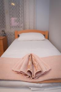 a bed with a pink blanket on top of it at Vila Balkan in Kikinda