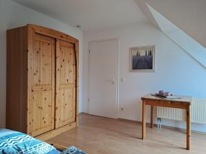 um quarto com um armário de madeira e uma mesa em Ruhepol am Meer - Apartment mit Balkon em Bastorf