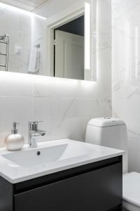 Baño blanco con lavabo y espejo en Bianca, en Turku