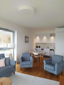 a living room with chairs and a table and a kitchen at Jurata Residence in Jurata