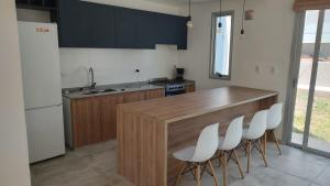 a kitchen with a wooden counter and white chairs at Duplex en barrio privado in Mendoza