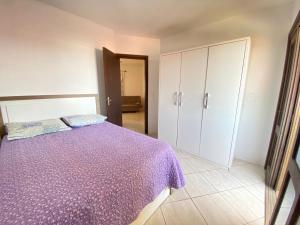 una camera con letto viola e armadi bianchi di Residencial Marítimos a Torres