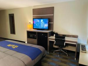 オマハにあるNew Victorian Inn & Suites Omahaのベッド、デスク、テレビが備わるホテルルームです。
