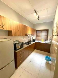 a kitchen with wooden cabinets and a white refrigerator at Relax Home 4-8 Pax Sunway Lagoon & Sunway Pyramid in Kampong Penaga