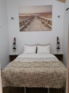 um quarto com uma cama e um quadro na parede em Chalé da Baía em Porto Covo