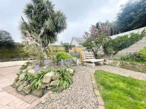 a garden with a bench and flowers in a yard at Cheerful Home Short Drive to Beautiful Beach in Redruth