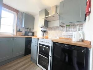a kitchen with a black oven and a black dishwasher at Cheerful Home Short Drive to Beautiful Beach in Redruth
