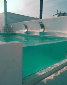 a swimming pool with green water in front of a building at Lindo piso en el corazón de Cádiz in Cádiz