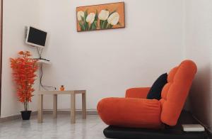 uma sala de estar com uma cadeira laranja e uma mesa em Malaguetor Home Colón em Málaga