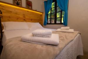 a bedroom with towels on a bed with a window at Casa aconchegante no coração do Bairro do Quilombo in São Bento do Sapucaí