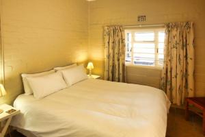 Un dormitorio con una gran cama blanca y una ventana en Oppi Stuppi Langebaan, en Langebaan
