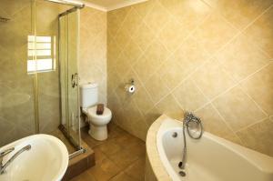 a bathroom with a tub and a toilet and a sink at Oppi Stuppi Langebaan in Langebaan