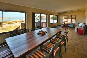 a dining room with a large wooden table and chairs at Oppi Stuppi Langebaan in Langebaan
