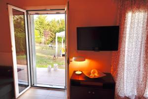 uma sala de estar com uma televisão e uma porta de vidro deslizante em Phivos Home & Garden em Messini