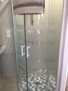 a glass shower in a bathroom with a checkered floor at Gîtes du château de la Motte in Joué-du-Plain