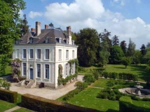 une grande maison blanche avec un jardin en face de celle-ci dans l'établissement Gîtes du château de la Motte, à Joué-du-Plain