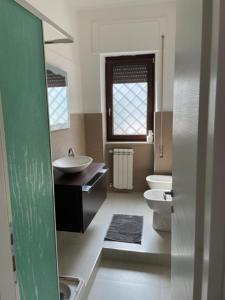 uma casa de banho com 2 WC, um lavatório e um espelho. em casa monte maggio em Cassino