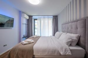 a bedroom with a large white bed with a window at Emirates Lux Apartment and Parking in Sofia