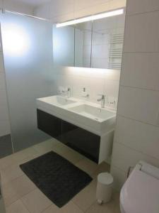 y baño con lavabo, espejo y aseo. en Modernes, exklusives Apartment im Dorf am Davoser See, Skikeller, Innenpool, Sauna, Balkon, en Davos