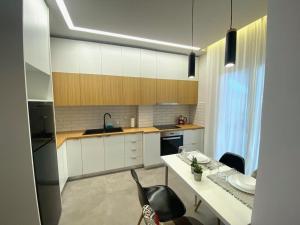 una cocina con armarios blancos y una mesa con sillas. en Piraeus Apartment for rent, en Pireo