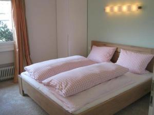 1 dormitorio con 1 cama con almohadas rosas y blancas en Schönes, exklusives Apartment, direkt am Luganersee, modernes Interieur, Außenpool, en Maroggia