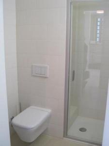 La salle de bains blanche est pourvue d'une douche et de toilettes. dans l'établissement Schönes, exklusives Apartment, direkt am Luganersee, modernes Interieur, Außenpool, à Maroggia
