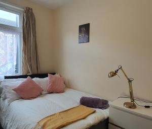 1 dormitorio con 1 cama con almohadas rosas y blancas en Coventry City House, en Parkside