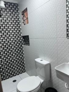 a white bathroom with a toilet and a sink at Hotel Ellos in Itaquaquecetuba