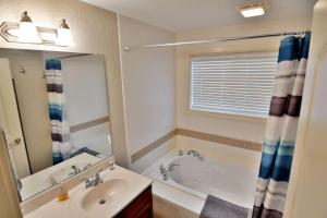 ein Badezimmer mit einer Badewanne, einem Waschbecken und einem Spiegel in der Unterkunft Unit 207 2 BDRM 2 BA condo in Birchwood