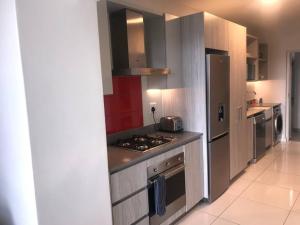 a kitchen with a stove and a refrigerator at Chic, Serviced one Bedroom Apartment in Rosebank in Johannesburg