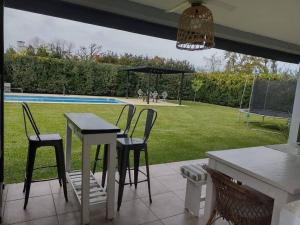 un patio con mesa, sillas y piscina en HARAS SANTA MARIA en Belén de Escobar