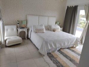 een slaapkamer met een wit bed en een stoel bij HARAS SANTA MARIA in Belén de Escobar
