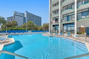 a swimming pool with chairs and a building at Ocean Park Resort - Oceana Resorts Vacation Rentals in Myrtle Beach