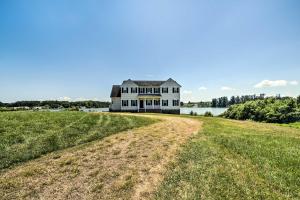 a large white house on top of a grassy field at Waterfront Montross Home with Private Boat Slip! in Montross