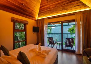 1 Schlafzimmer mit einem Bett und einem Balkon mit Stühlen in der Unterkunft Chembarathi Wayanad Boutique Resort in Vaduvanchal