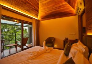 um quarto com uma cama e uma varanda em Chembarathi Wayanad Boutique Resort em Vaduvanchal