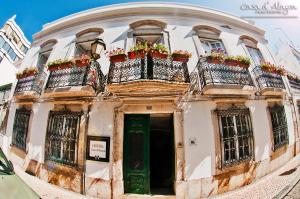 un edificio antiguo con 2 balcones con flores. en Hostel Casa d'Alagoa, en Faro
